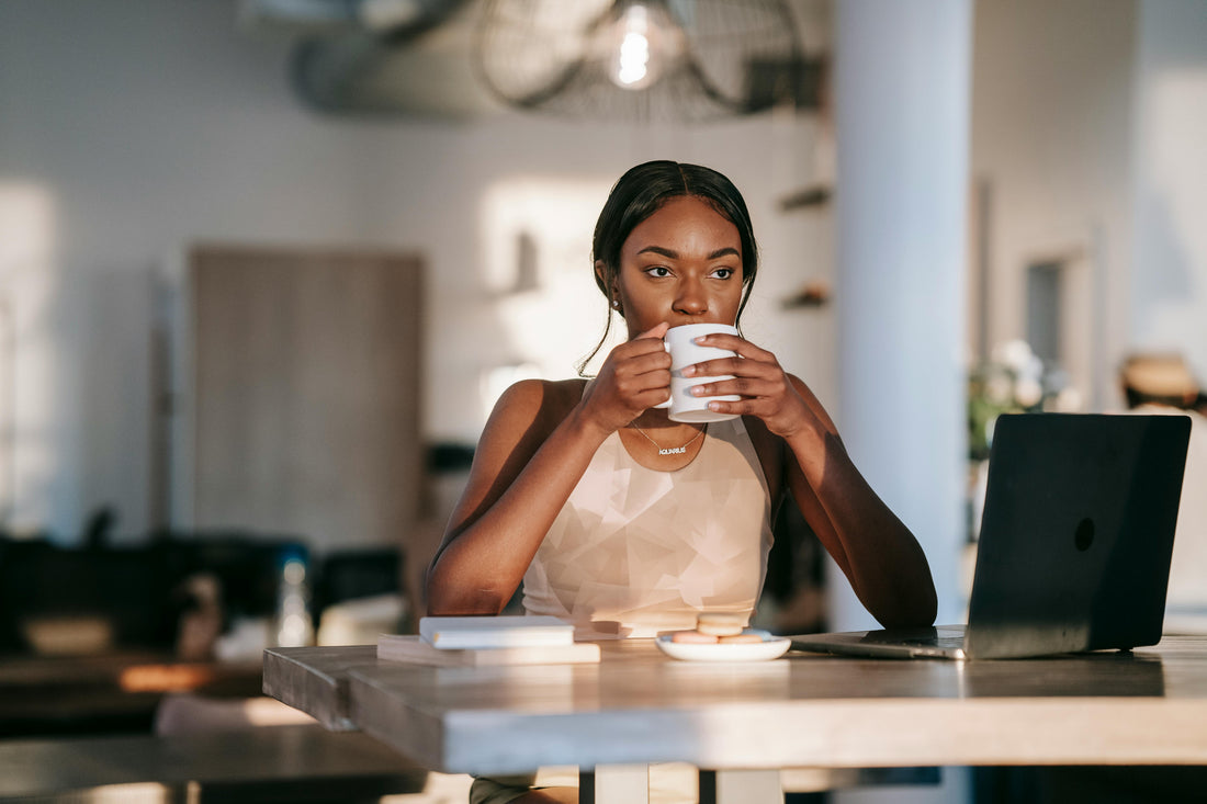 Femme concentrée en télétravail, tasse de café à la main, dans un espace lumineux et organisé